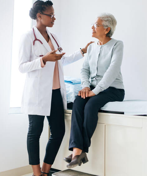 female doctor talking to a female elder patient sitting on a hospital bed