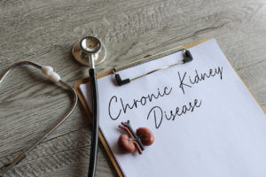 Stethoscope, kidney model and paper clipboard with text Chronic Kidney Disease.